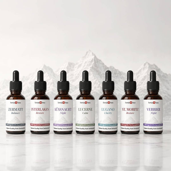 Formula Swiss CBD Öl-Kollektion mit sieben Bernstein-Tropfflaschen vor einem Schweizer Berghintergrund.