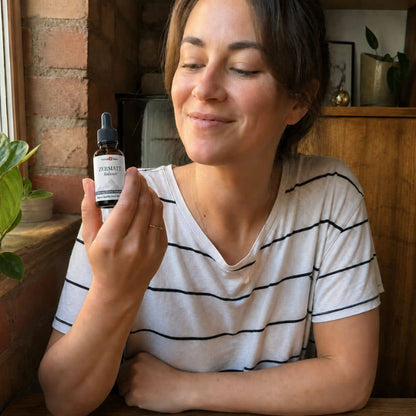Woman holding a bottle of Zermatt CBD oil in a cozy indoor setting.